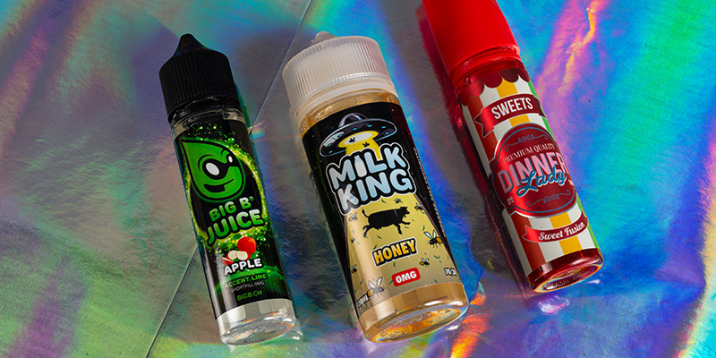 Bunte E-Liquid Flaschen Sortiment Drei bunte E-Liquid Flaschen mit den Etiketten Big B Juice Apple, Milk King Honey und Dinner Lady Sweets