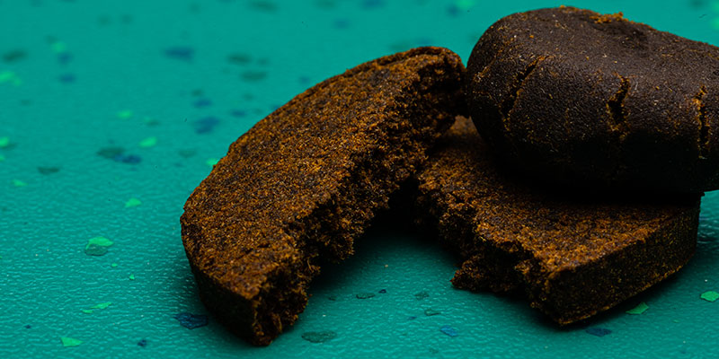 CBD Hash aus der Schweiz, dunkle gepresste Harzstücke mit krümeliger Struktur, legaler THC-Gehalt unter 1%